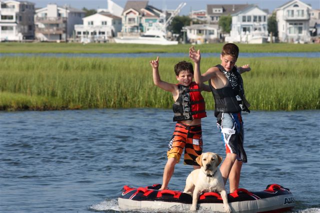 Two boys and cream-colored English Labrador standing on a raft